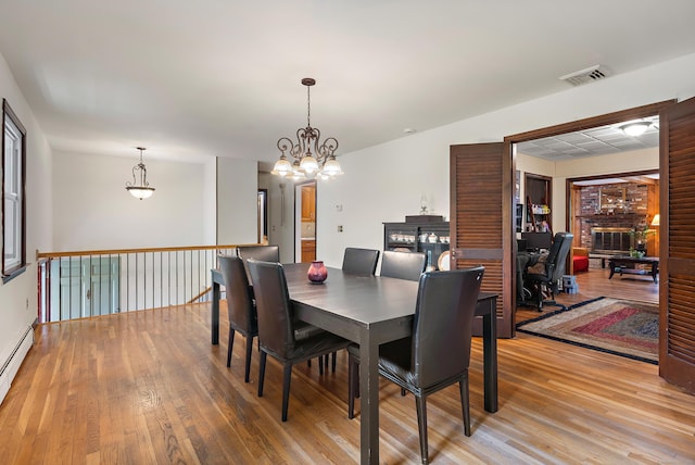 205 Luther Dr, Southbury, CT 06488 - dining space with a fireplace, light wood-style flooring, a chandelier, and baseboard heating