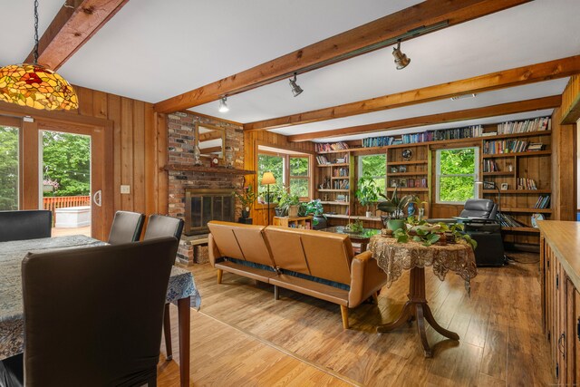 205 Luther Dr, Southbury, CT 06488 - living room with track lighting, beamed ceiling, wooden walls, light wood finished floors, and a brick fireplace