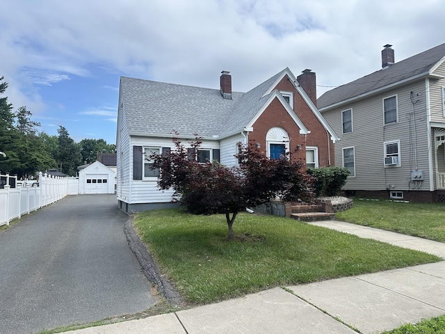 27 Woodbridge Ave, East Hartford, CT 06108 - view of front facade with a detached garage, an outbuilding, cooling unit, driveway, and a chimney