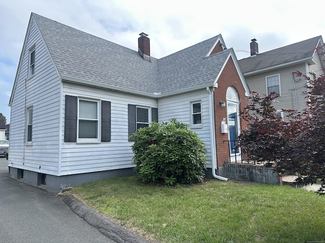27 Woodbridge Ave, East Hartford, CT 06108 - view of home's exterior featuring roof with shingles, a chimney, and a lawn