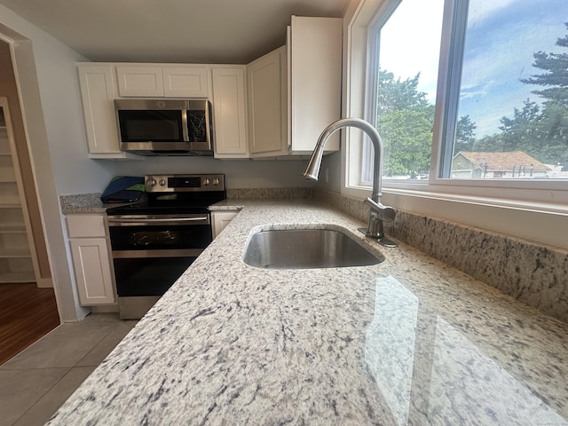 27 Woodbridge Ave, East Hartford, CT 06108 - kitchen featuring stainless steel appliances, light stone counters, white cabinets, and tile patterned flooring