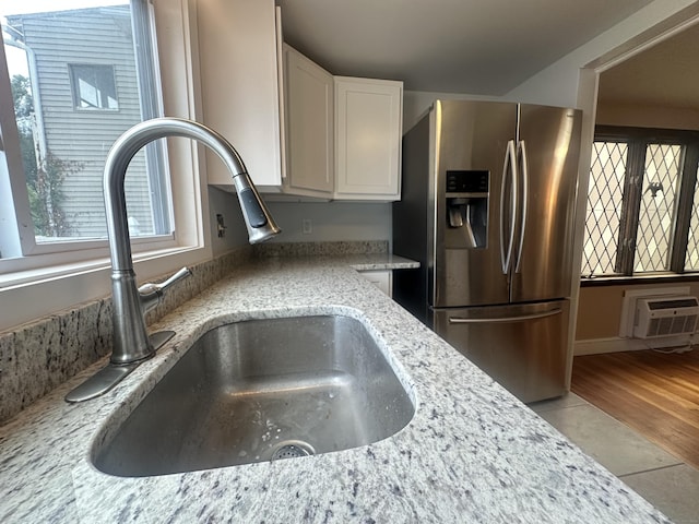 27 Woodbridge Ave, East Hartford, CT 06108 - kitchen view of stainless steel refrigerator with ice dispenser, an AC wall unit, white cabinets, and light stone counters
