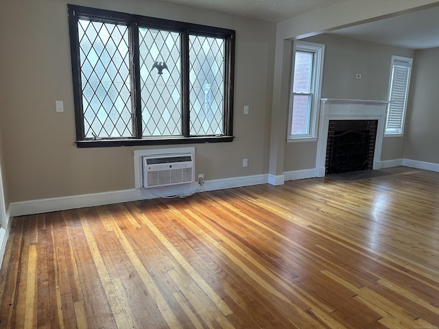 27 Woodbridge Ave, East Hartford, CT 06108 - unfurnished living room featuring hardwood / wood-style floors, an AC wall unit, and a fireplace