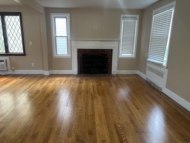 27 Woodbridge Ave, East Hartford, CT 06108 - unfurnished living room with radiator heating unit, a fireplace, wood finished floors, and a wall mounted AC