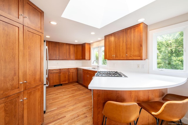 100 N Lake Shore Dr, Brookfield, CT 06804 - kitchen with brown cabinetry, light wood-type flooring, a peninsula, stainless steel appliances, and recessed lighting