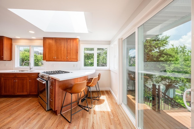 100 N Lake Shore Dr, Brookfield, CT 06804 - kitchen featuring gas stove, brown cabinets, light wood-type flooring, a breakfast bar, and recessed lighting