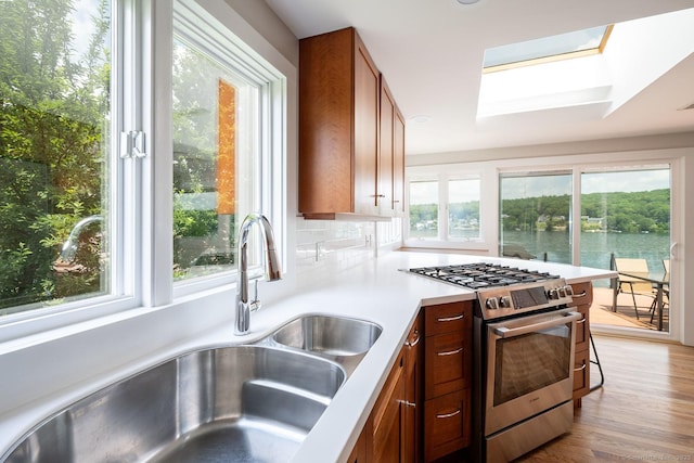 100 N Lake Shore Dr, Brookfield, CT 06804 - kitchen featuring stainless steel gas range, a skylight, light countertops, light wood-style floors, and brown cabinets