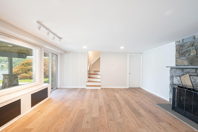 100 N Lake Shore Dr, Brookfield, CT 06804 - unfurnished living room with stairway, a stone fireplace, light wood-style flooring, and rail lighting