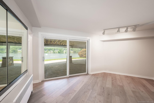 100 N Lake Shore Dr, Brookfield, CT 06804 - empty room with radiator heating unit, rail lighting, a water view, and light wood-style floors