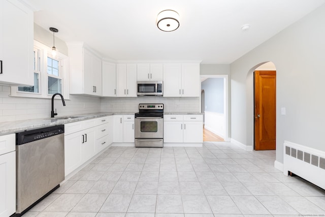 19 Robert St, Hamden, CT 06514 - kitchen featuring stainless steel appliances, radiator, backsplash, light stone countertops, and arched walkways