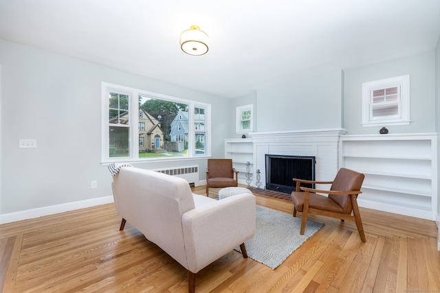 19 Robert St, Hamden, CT 06514 - living room featuring radiator, light wood-type flooring, and a brick fireplace