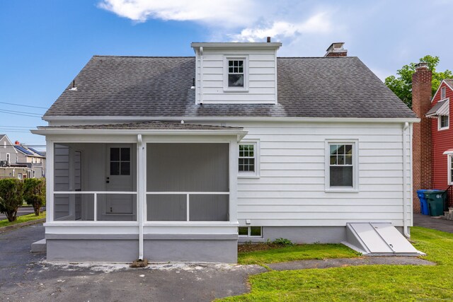 19 Robert St, Hamden, CT 06514 - back of property with a sunroom, a shingled roof, a chimney, and a lawn
