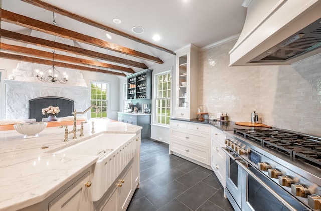 509 Main St N, Woodbury, CT 06798 - kitchen featuring custom range hood, range with two ovens, light stone countertops, dark tile patterned flooring, and beam ceiling