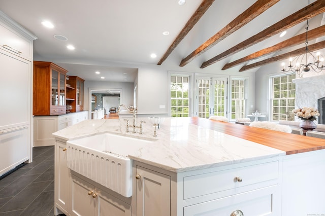 509 Main St N, Woodbury, CT 06798 - kitchen with a large island with sink, open floor plan, glass insert cabinets, recessed lighting, and light stone counters