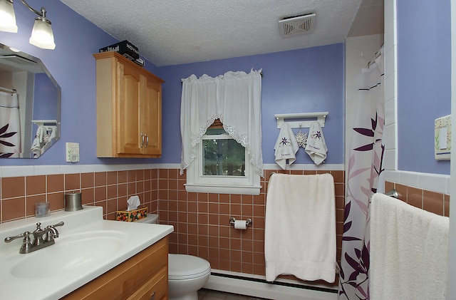 134 Valley Crest Dr, Wethersfield, CT 06109 - bathroom with tile walls, baseboard heating, vanity, a wainscoted wall, and a textured ceiling