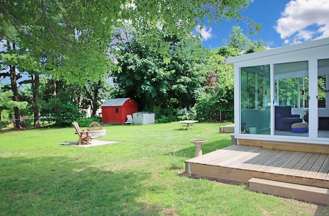 134 Valley Crest Dr, Wethersfield, CT 06109 - view of grassy yard with a storage unit, a sunroom, an outdoor fire pit, and a deck