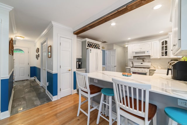 2 Bronson Rd, Prospect, CT 06712 - kitchen featuring white appliances, a peninsula, white cabinets, light stone counters, and a kitchen breakfast bar