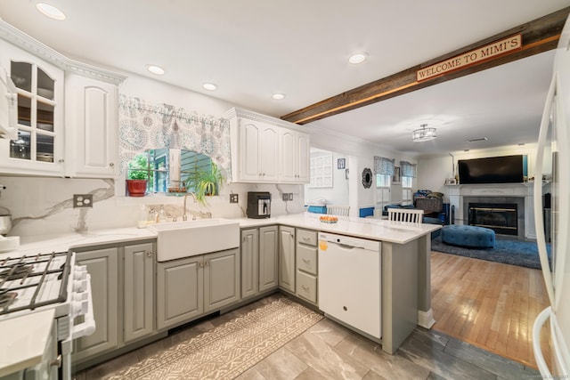 2 Bronson Rd, Prospect, CT 06712 - kitchen with white dishwasher, a peninsula, a glass covered fireplace, white cabinetry, and light countertops