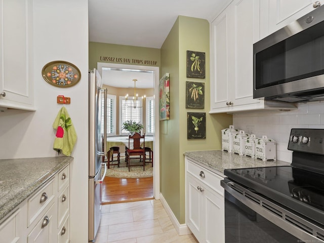 51 Hale Ln Unit 51, Darien, CT 06820 - kitchen with appliances with stainless steel finishes, white cabinetry, tasteful backsplash, a chandelier, and light stone countertops