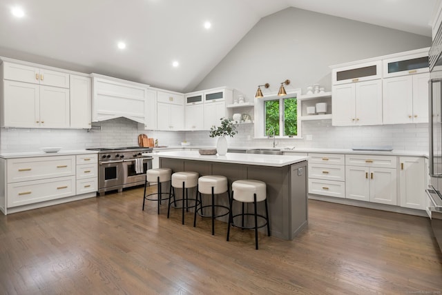 3663 Congress St, Fairfield, CT 06824 - kitchen with range with two ovens, open shelves, a breakfast bar, white cabinets, and high vaulted ceiling