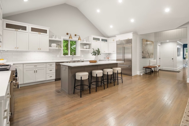 3663 Congress St, Fairfield, CT 06824 - kitchen with appliances with stainless steel finishes, open shelves, a center island, a breakfast bar area, and white cabinets