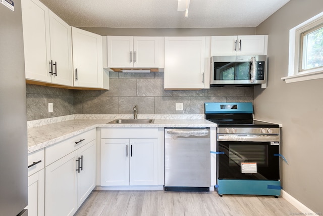 118 Sheraton Ln Unit 118, Norwich, CT 06360 - kitchen with stainless steel appliances, light wood-type flooring, white cabinets, and backsplash