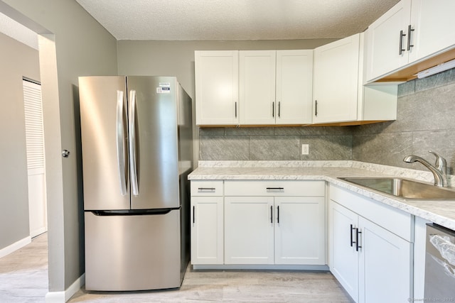 118 Sheraton Ln Unit 118, Norwich, CT 06360 - kitchen with stainless steel appliances, light wood-style floors, tasteful backsplash, white cabinets, and a textured ceiling