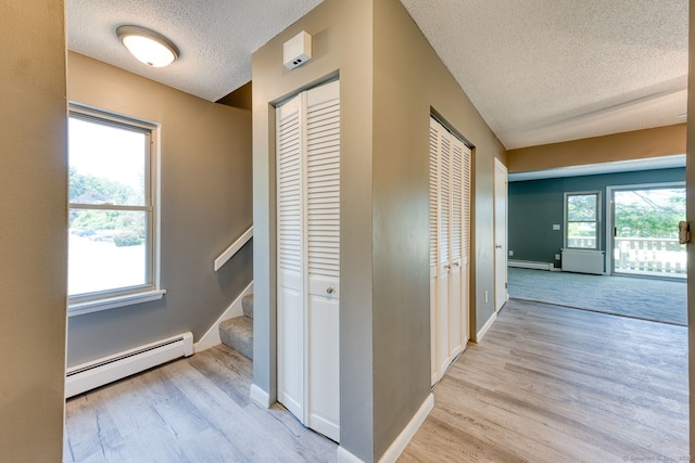118 Sheraton Ln Unit 118, Norwich, CT 06360 - corridor with baseboard heating, a textured ceiling, light wood-style flooring, and stairway