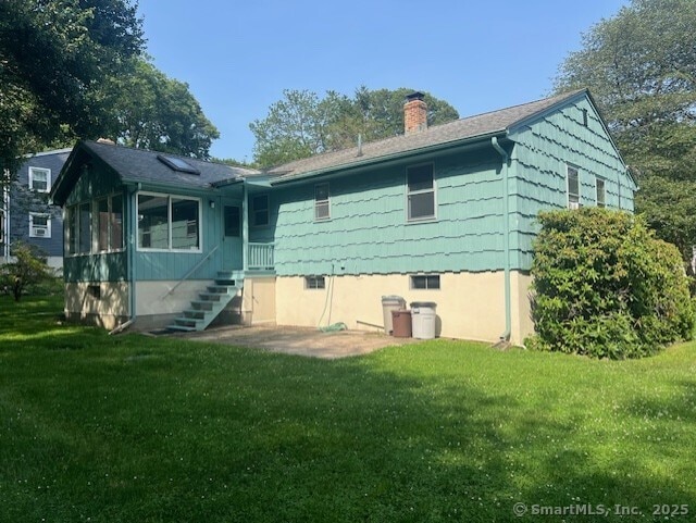 35 Corey Ln, East Lyme, CT 06357 - back of property with a chimney, a lawn, and a sunroom