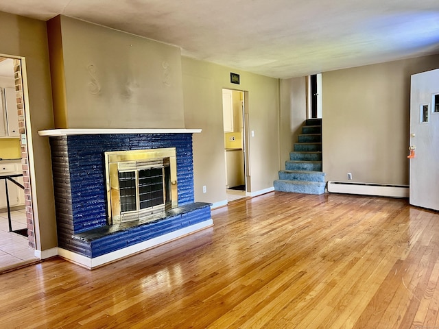 239 Bates Dr, Cheshire, CT 06410 - unfurnished living room featuring a baseboard radiator, wood-type flooring, stairs, and a glass covered fireplace