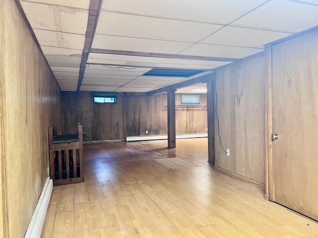 239 Bates Dr, Cheshire, CT 06410 - below grade area featuring wood finished floors, a baseboard radiator, wooden walls, a drop ceiling, and a baseboard heating unit