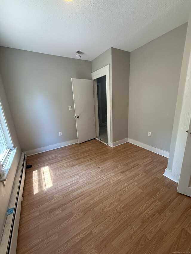 14 Market St, New Haven, CT 06513 - unfurnished bedroom with a baseboard heating unit, light wood finished floors, and a textured ceiling