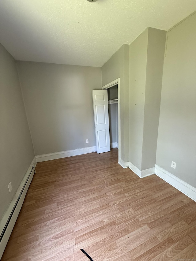 14 Market St, New Haven, CT 06513 - unfurnished bedroom featuring a baseboard radiator, light wood finished floors, a closet, and a textured ceiling