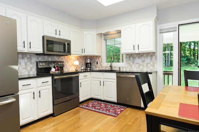 76 Highland Dr Unit 76, Monroe, CT 06468 - kitchen with stainless steel appliances, white cabinetry, light wood-style flooring, decorative backsplash, and dark countertops