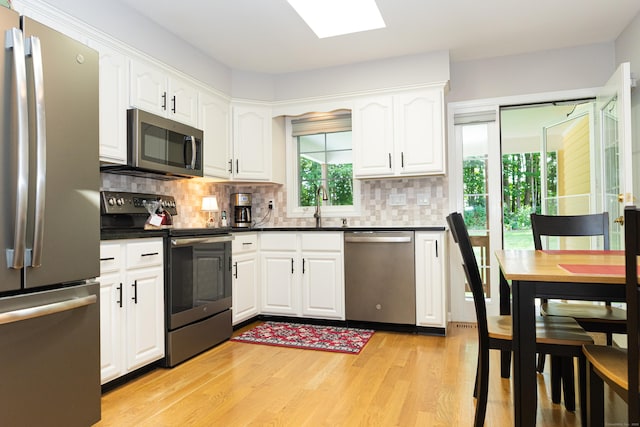 76 Highland Dr Unit 76, Monroe, CT 06468 - kitchen featuring appliances with stainless steel finishes, light wood-style flooring, dark countertops, white cabinets, and decorative backsplash