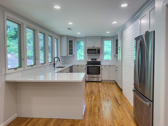 6 Jeffro Dr, Ridgefield, CT 06877 - kitchen featuring appliances with stainless steel finishes, a peninsula, light countertops, glass insert cabinets, and light wood-type flooring