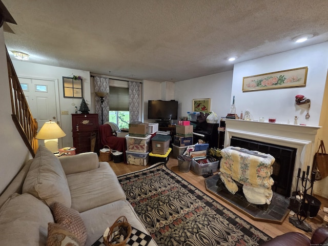 16 Seymour Rd Unit 2C, East Granby, CT 06026 - living area featuring a fireplace with raised hearth, wood finished floors, a textured ceiling, stairway, and recessed lighting