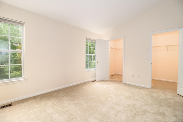 2303 Eaton Ct Unit 2303, Danbury, CT 06811 - unfurnished bedroom featuring a walk in closet, multiple windows, carpet floors, and vaulted ceiling