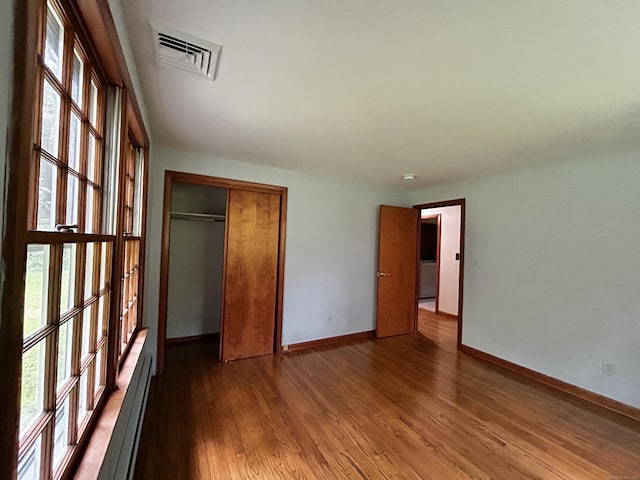 364 Locust Rd, Harwinton, CT 06791 - unfurnished bedroom with multiple windows, wood finished floors, a closet, and a baseboard heating unit