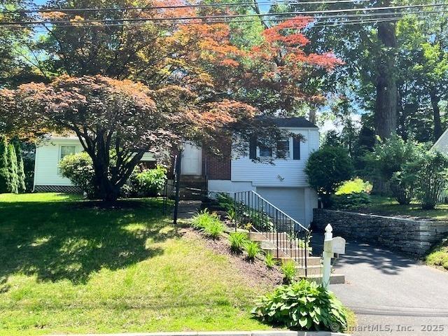 49 Geneva Ave, West Hartford, CT 06107 - view of property hidden behind natural elements featuring a garage, a front yard, and driveway