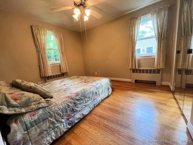49 Geneva Ave, West Hartford, CT 06107 - bedroom featuring radiator heating unit, wood finished floors, multiple windows, and a ceiling fan