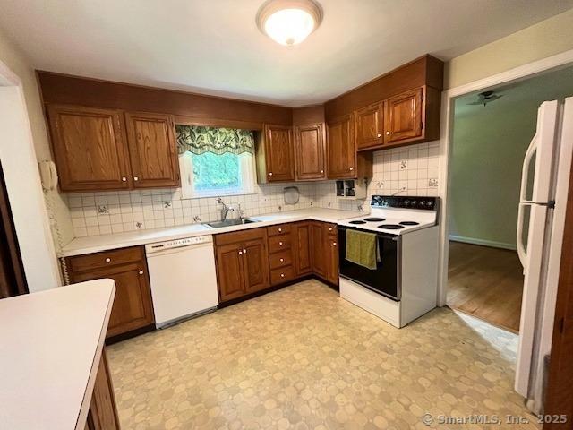 49 Geneva Ave, West Hartford, CT 06107 - kitchen with white appliances, light countertops, tasteful backsplash, and brown cabinetry