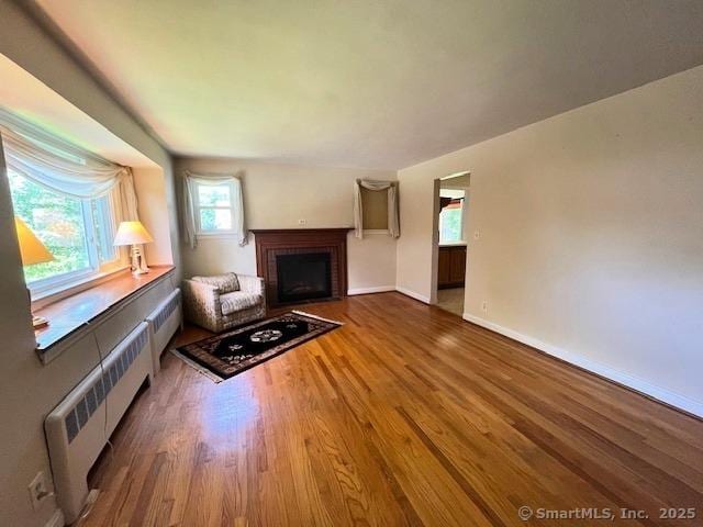 49 Geneva Ave, West Hartford, CT 06107 - unfurnished living room with radiator, a brick fireplace, and wood finished floors