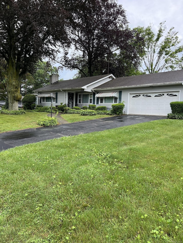 ranch-style home featuring driveway, an attached garage, a front lawn, and a chimney