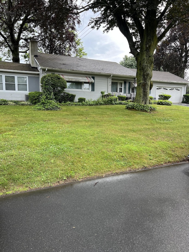view of front facade with a front lawn, a garage, and a chimney