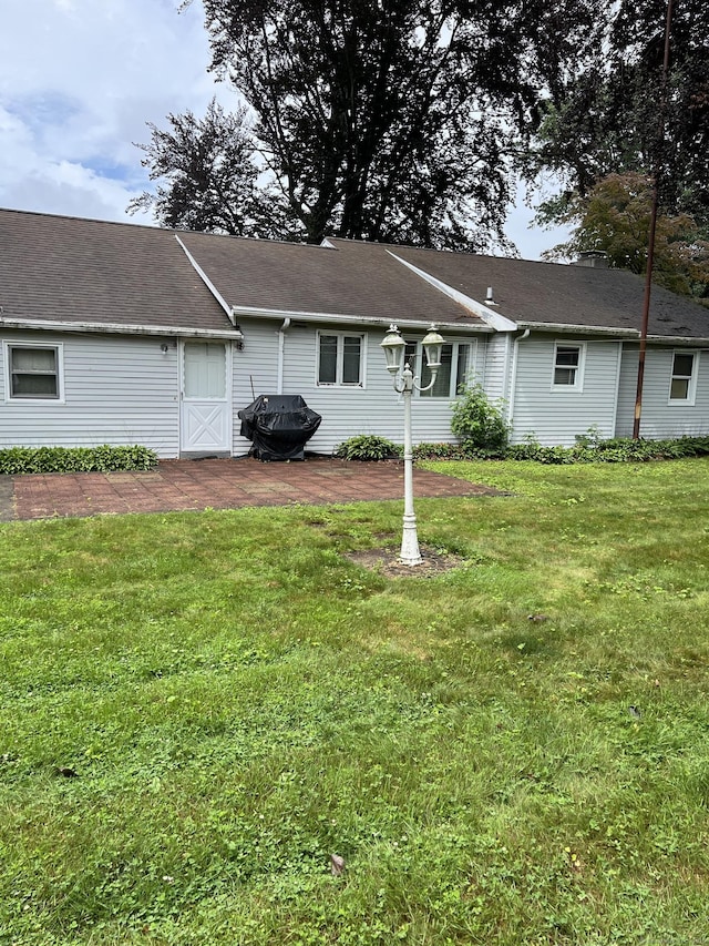 rear view of property featuring a yard and a patio area