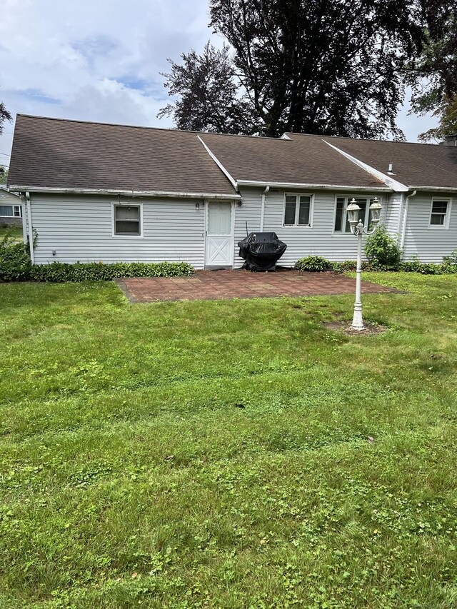 back of house with a lawn and a patio