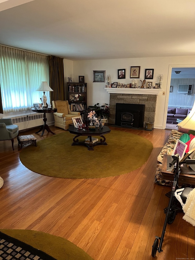 living area featuring a fireplace, wood finished floors, and radiator heating unit