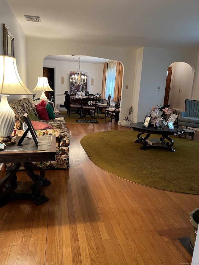 living room featuring arched walkways, a chandelier, and wood-type flooring