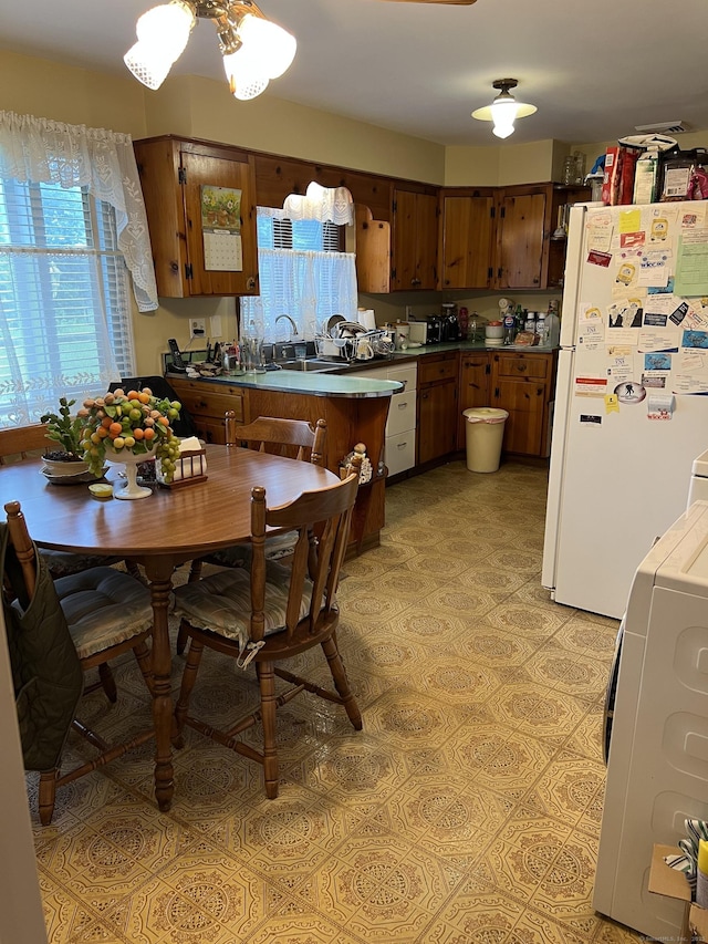 kitchen featuring freestanding refrigerator, a peninsula, and light flooring